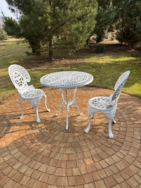 Weißes Romantic-Gartenmöbelset mit zwei Stühlen auf einer runden Gartenterrasse